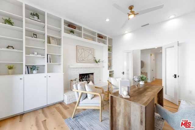 office with a brick fireplace, light hardwood / wood-style flooring, and ceiling fan