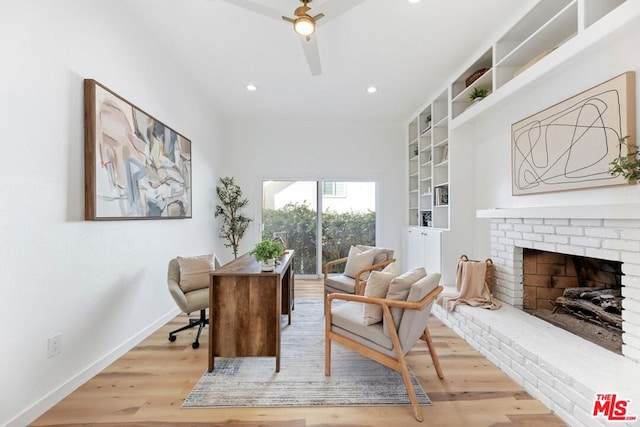 office area featuring ceiling fan, light hardwood / wood-style flooring, and a brick fireplace