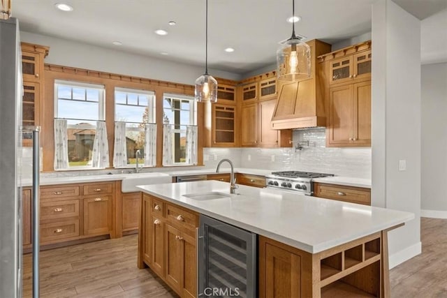 kitchen featuring wine cooler, a kitchen island with sink, light hardwood / wood-style flooring, and decorative backsplash