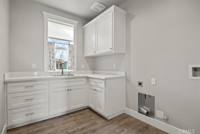 clothes washing area with sink, cabinets, electric dryer hookup, hookup for a gas dryer, and light wood-type flooring