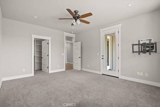 unfurnished bedroom featuring ceiling fan, a walk in closet, light carpet, and a closet