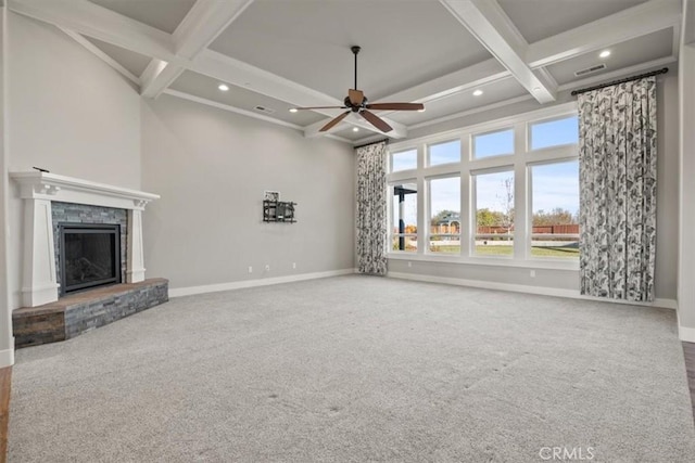 unfurnished living room with a stone fireplace, beamed ceiling, carpet floors, and coffered ceiling