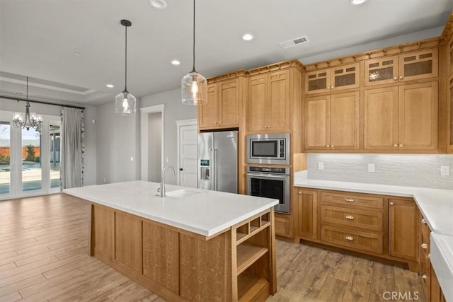 kitchen with light hardwood / wood-style floors, sink, stainless steel appliances, and a kitchen island with sink