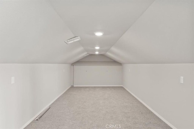 additional living space featuring light carpet and vaulted ceiling