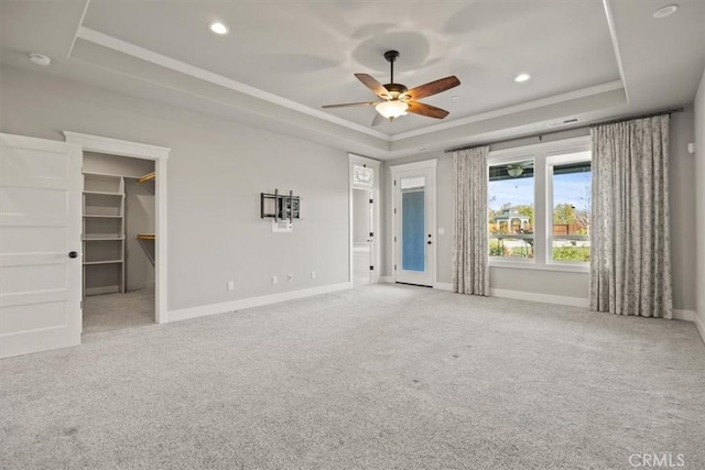 interior space with a tray ceiling, ceiling fan, and ornamental molding