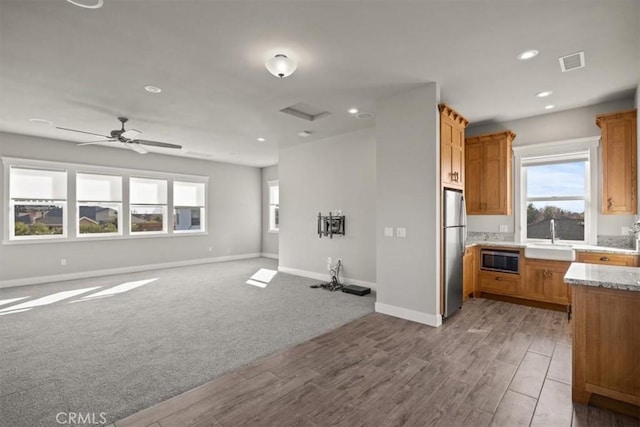 kitchen featuring sink, ceiling fan, appliances with stainless steel finishes, light hardwood / wood-style floors, and light stone counters