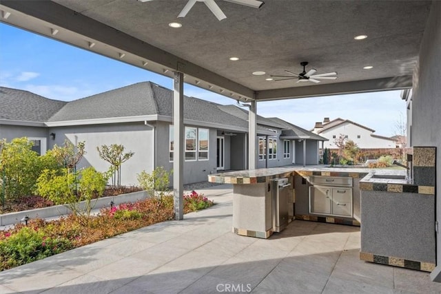 view of patio featuring ceiling fan, exterior kitchen, and an outdoor wet bar