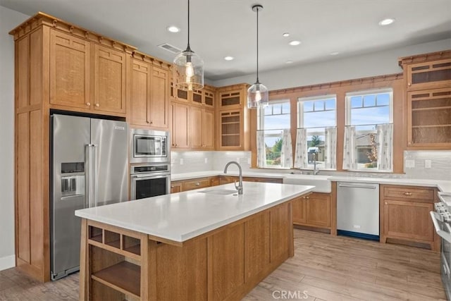 kitchen featuring sink, a kitchen island with sink, light hardwood / wood-style flooring, pendant lighting, and high quality appliances