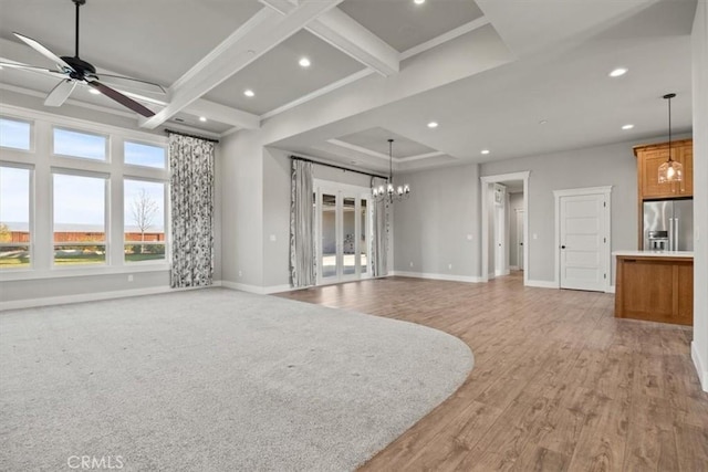 unfurnished living room with beam ceiling, coffered ceiling, light hardwood / wood-style floors, and ceiling fan with notable chandelier