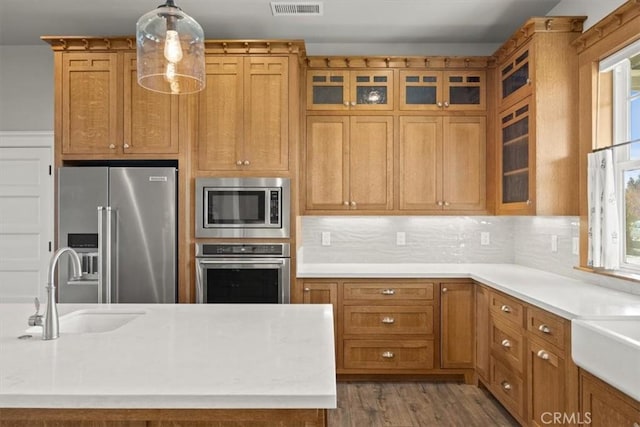 kitchen with sink, hanging light fixtures, stainless steel appliances, backsplash, and hardwood / wood-style floors