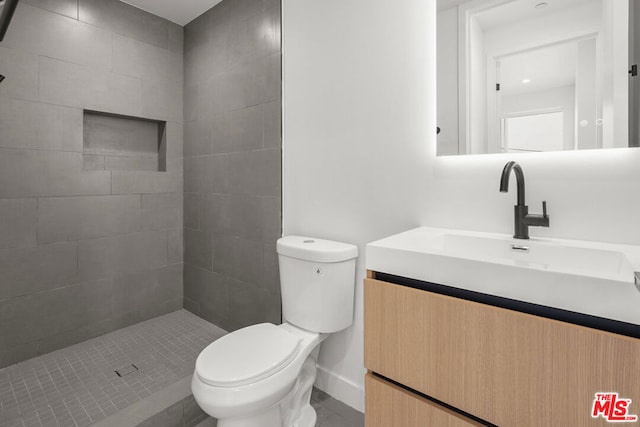 bathroom with tiled shower, vanity, and toilet