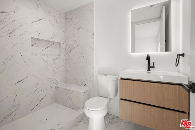 bathroom with tiled shower, vanity, and toilet