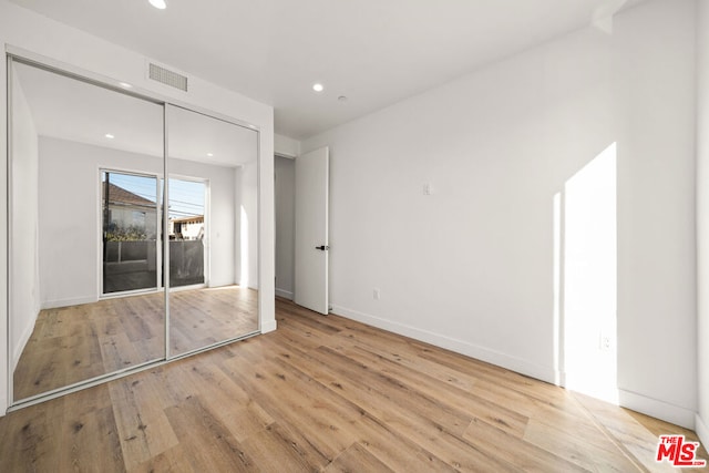 unfurnished bedroom featuring light wood-type flooring and a closet