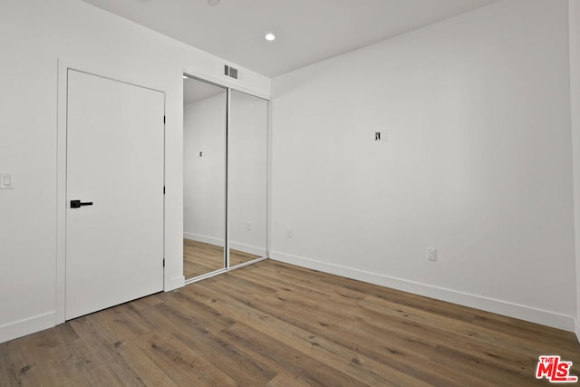 unfurnished bedroom with a closet and hardwood / wood-style flooring