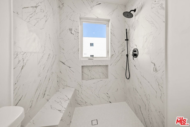 bathroom with a tile shower and toilet