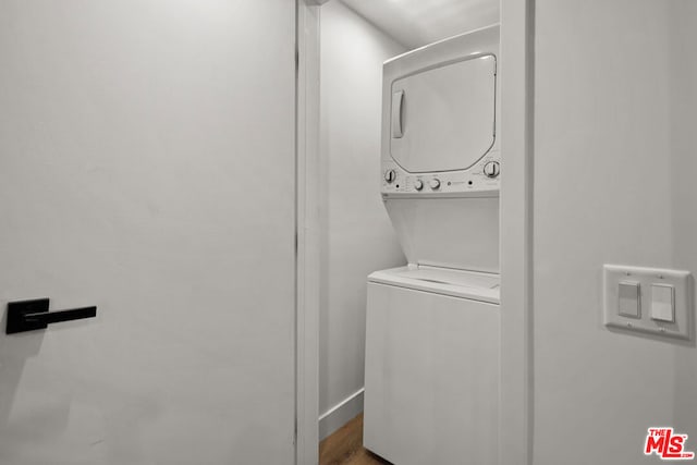 laundry room featuring stacked washer and dryer and hardwood / wood-style flooring