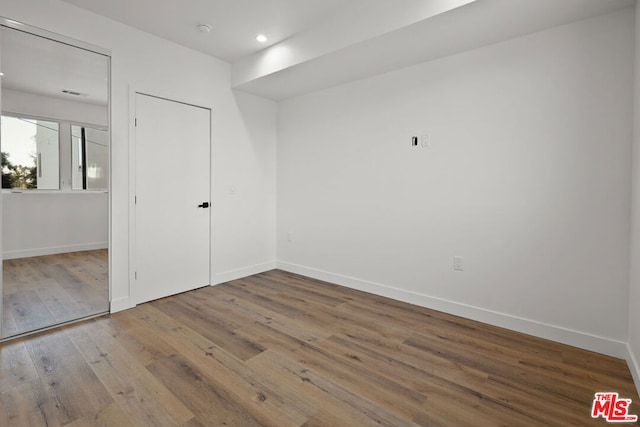 unfurnished bedroom featuring hardwood / wood-style floors and a closet