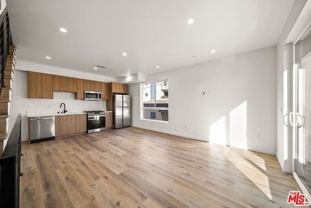 kitchen with light wood-type flooring, stainless steel appliances, and sink