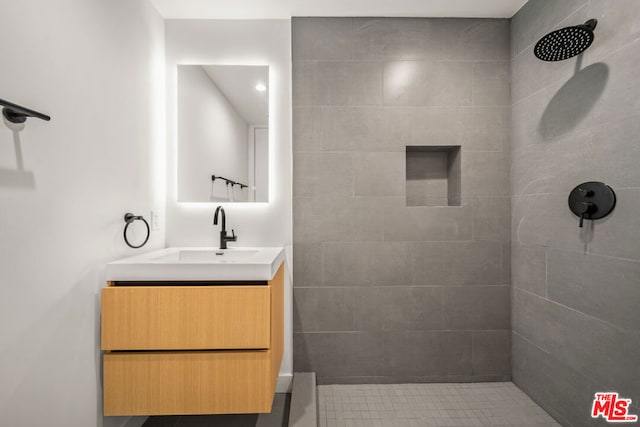 bathroom featuring tiled shower and vanity