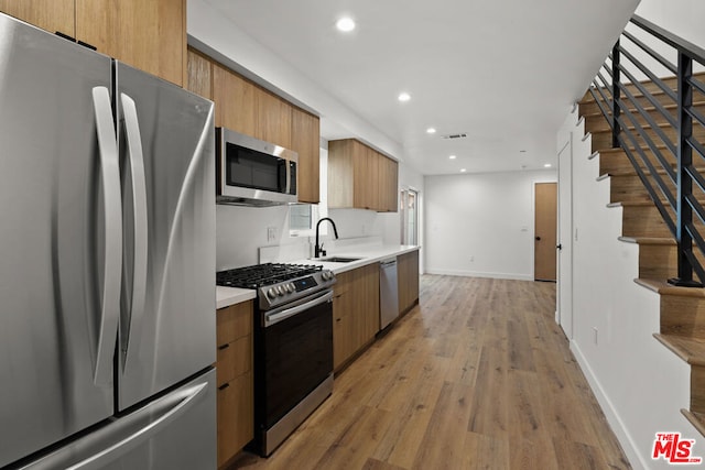 kitchen with stainless steel appliances, light hardwood / wood-style flooring, and sink