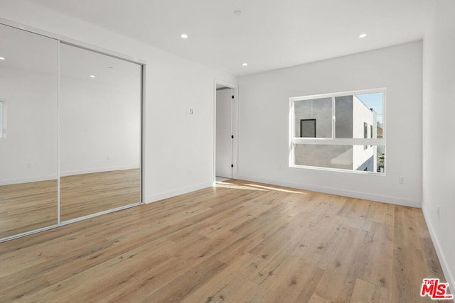 unfurnished bedroom featuring light hardwood / wood-style floors and a closet