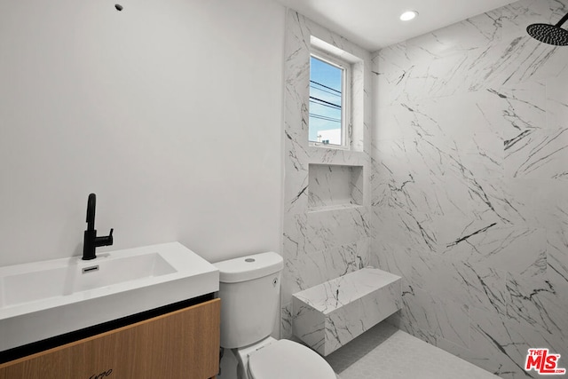 bathroom with a tile shower, vanity, and toilet