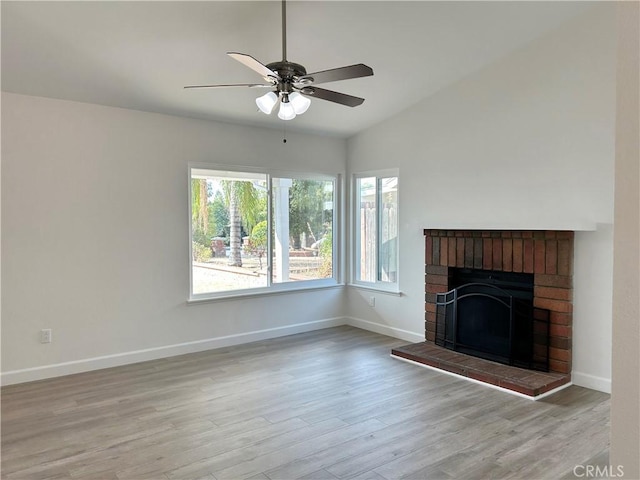 unfurnished living room featuring a fireplace, light hardwood / wood-style floors, vaulted ceiling, and ceiling fan