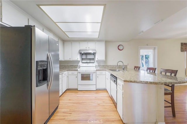 kitchen with light hardwood / wood-style floors, a kitchen bar, white appliances, and kitchen peninsula