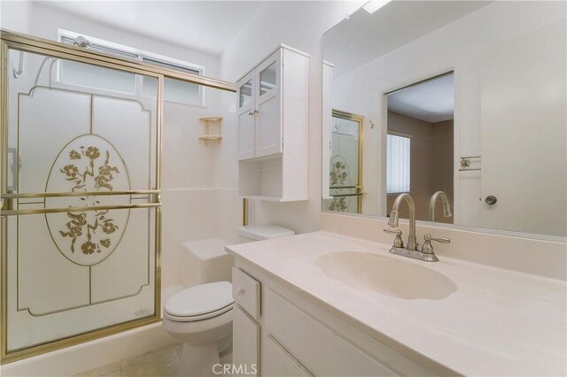 bathroom featuring tile patterned flooring, vanity, toilet, and a shower with door