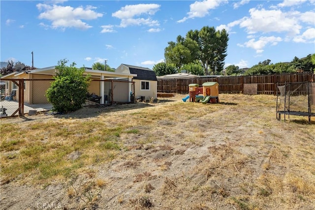 view of yard with a playground, a trampoline, and a shed