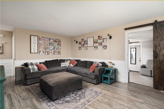 living room with wood-type flooring, ceiling fan, and a barn door