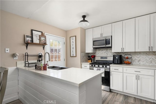 kitchen with sink, kitchen peninsula, appliances with stainless steel finishes, and white cabinetry