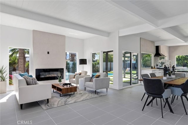 tiled living room featuring a fireplace, beam ceiling, and plenty of natural light