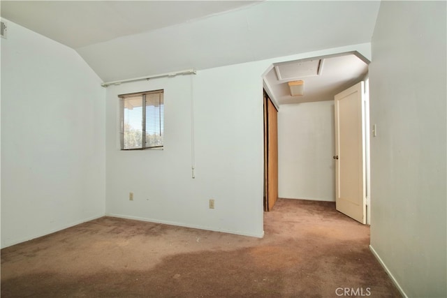 carpeted empty room with vaulted ceiling