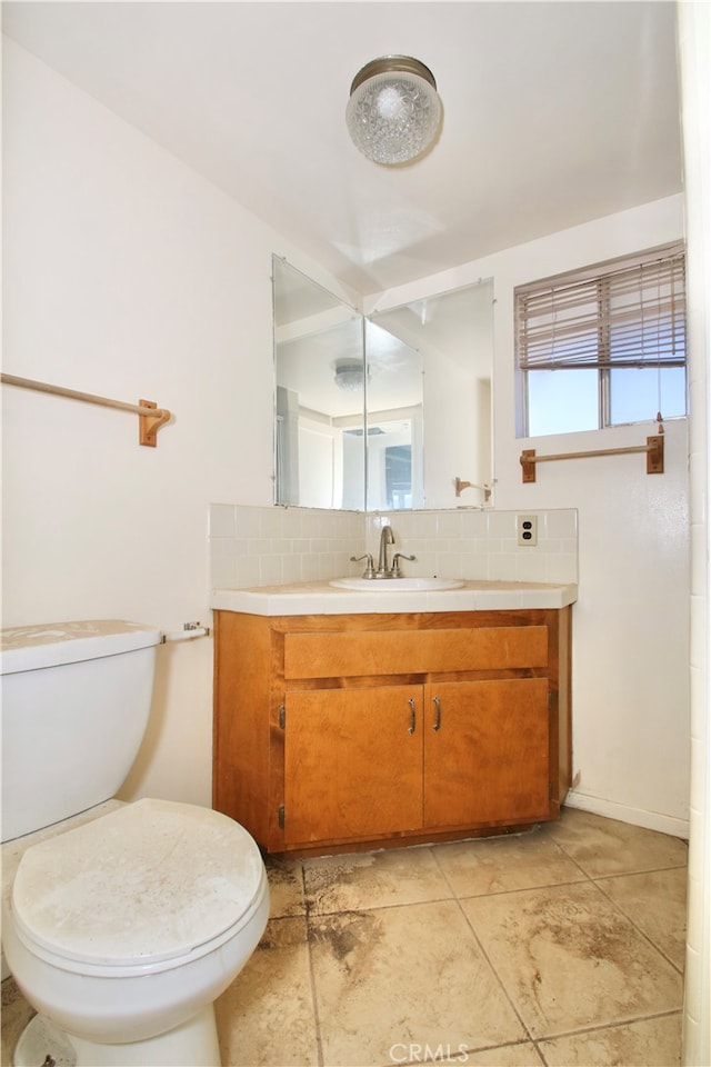 bathroom featuring vanity, toilet, and backsplash