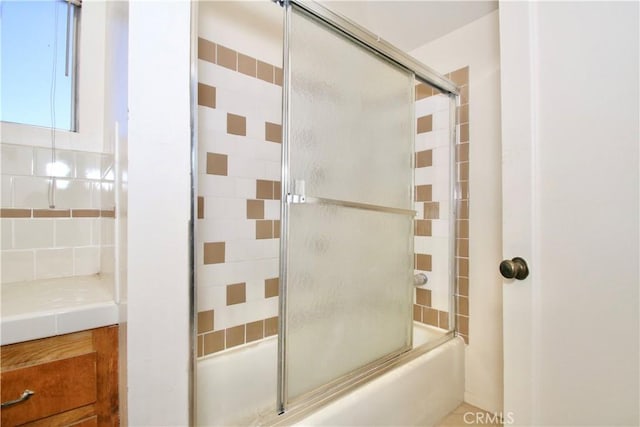 bathroom with tasteful backsplash and combined bath / shower with glass door