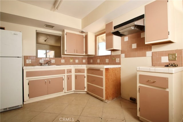 kitchen featuring decorative backsplash, white fridge, light tile patterned floors, and a wealth of natural light