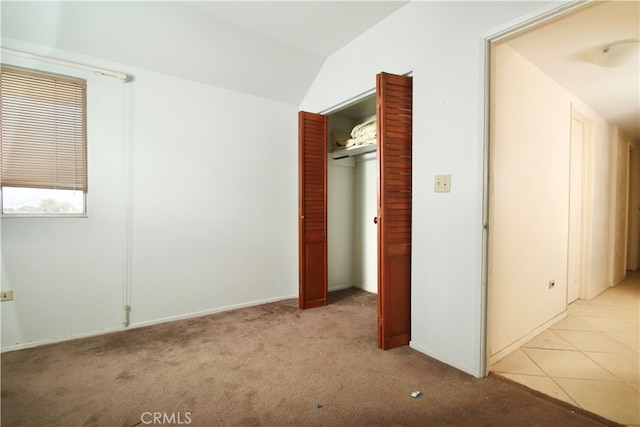 unfurnished bedroom featuring lofted ceiling, light carpet, and a closet