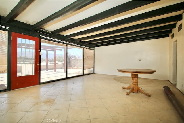 empty room featuring beamed ceiling and light tile patterned floors