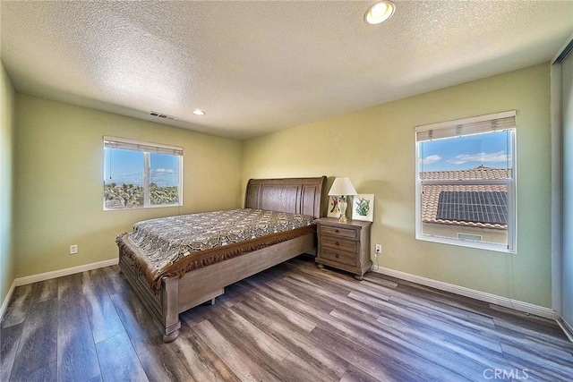 bedroom featuring a textured ceiling and dark hardwood / wood-style flooring