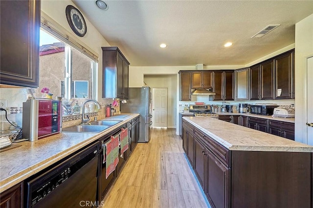 kitchen featuring a textured ceiling, stainless steel appliances, sink, light hardwood / wood-style flooring, and a center island