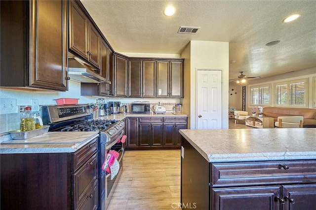 kitchen with dark brown cabinets, light hardwood / wood-style floors, a textured ceiling, and stainless steel range with gas stovetop