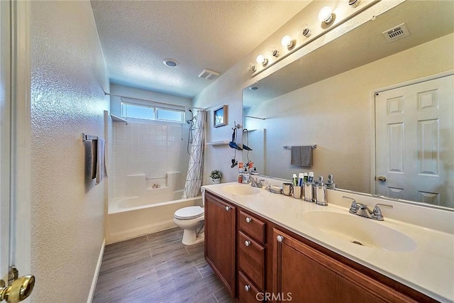 full bathroom featuring wood-type flooring, a textured ceiling, toilet, vanity, and shower / tub combo