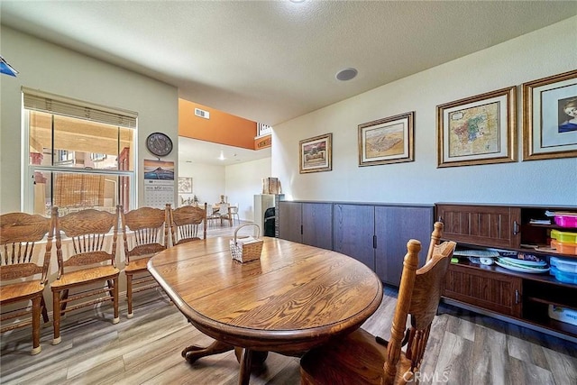 dining space with a textured ceiling and hardwood / wood-style flooring