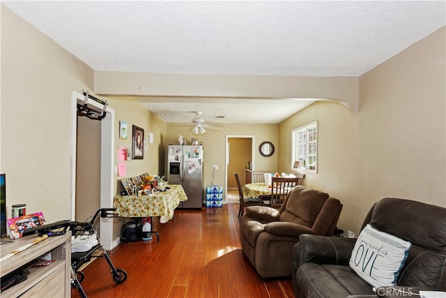 living room featuring ceiling fan, a textured ceiling, and dark hardwood / wood-style flooring