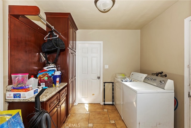 clothes washing area with cabinets, washing machine and dryer, and light tile patterned floors