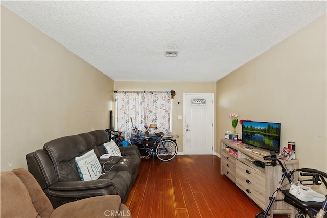 living room featuring dark wood-type flooring and a textured ceiling