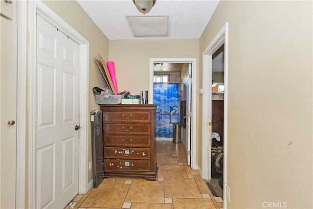 hallway with a textured ceiling and light tile patterned floors