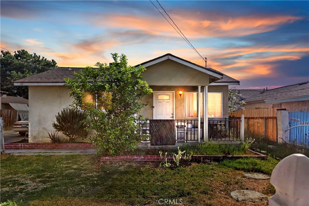 bungalow-style house featuring covered porch and a yard