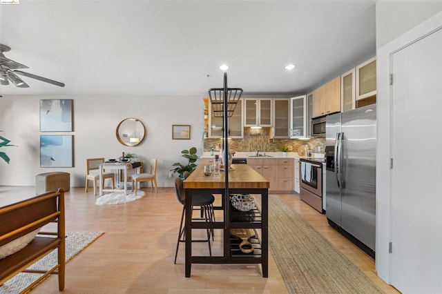 kitchen with light brown cabinets, tasteful backsplash, sink, light hardwood / wood-style floors, and stainless steel appliances